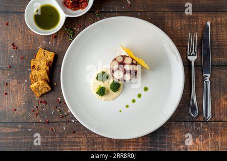 Octopus terrine or octopus carpaccio with sauces on a white porcelain plate Stock Photo