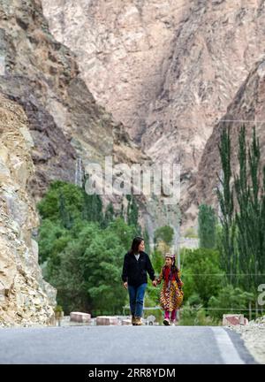 210520 -- AKTO, May 20, 2021 -- Chen Fangying escorts a student home at Alimalik Village of Akto County, northwest China s Xinjiang Uygur Autonomous Region, May 12, 2021. Chen Fangying, a 24-year-old village teacher, is from southwest China s Guizhou Province. When she graduated from college two years ago, she chose to become a teacher in Xinjiang. The primary school where Chen teaches is located in the Kunlun Mountains, more than 1,800 kilometers away from Xinjiang s capital city Urumqi. For me, this is the life I should live in my twenties, said Chen. Chen Fangying has more than ten classes Stock Photo