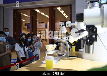 210523 -- TIANJIN, May 23, 2021 -- Visitors watch a robot making coffee at the fifth World Intelligence Congress at Tianjin Meijiang Conference and Exhibition Center in north China s Tianjin, May 23, 2021. The fifth World Intelligence Congress, a major artificial intelligence AI event in China, kicked off in north China s Tianjin Municipality on Thursday, highlighting frontier AI technologies and applications. The four-day event, with the theme of New Era of Intelligence: Empowering New Development, Fostering New Pattern, has attracted the participation of over 240 AI companies and institution Stock Photo