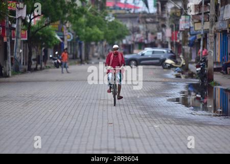 210529 -- ASSAM, May 29, 2021 -- A man wearing a face mask rides a bike in a closed market during a lockdown in Nagaon district of India s northeastern state of Assam, May 29, 2021. India s COVID-19 tally reached 27,729,247 on Saturday, with 173,790 new cases added during the past 24 hours, said the federal health ministry. Str/Xinhua INDIA-ASSAM-COVID-19-LOCKDOWN JavedxDar PUBLICATIONxNOTxINxCHN Stock Photo