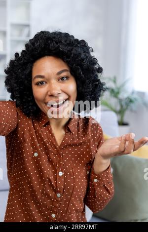 Close-up photo of an African-American woman talking to a camera online from home, recording her blog and podcast. Vertical photo. Stock Photo