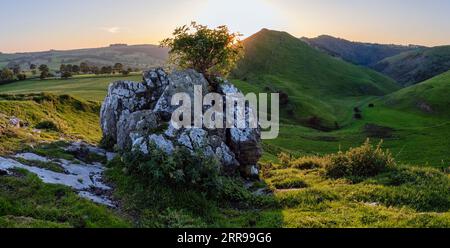 The sun setting behind Thorpe Cloud seen from Hamston Hill, Peak District National Park, Derbyshire, England Stock Photo