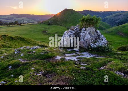The sun setting behind Thorpe Cloud seen from Hamston Hill, Peak District National Park, Derbyshire, England Stock Photo