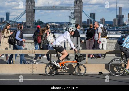 A man riding a Brompton folding bicycle across London Bridge, London, UK.  17 Jul 2023 Stock Photo