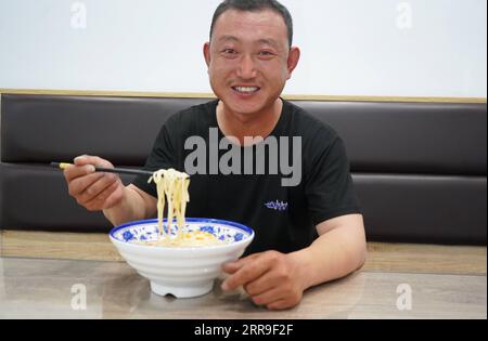 210613 -- XINGTAI, June 13, 2021 -- Local farmer Su Chuan has noodles as the day s meal in Xingtai, north China s Hebei Province, June 9, 2021. With the summer wheat harvest underway, farmers in north China s Xingtai have been busy in the fields to reap the year s premium grains. In Xingtai, a total of 65 farmers have joined the Jinshahe specialized cooperative that provides them with technical guidance in crop harvesting. The cooperative will sell freshly harvested crops to a local noodle factory where staple products are made and sold to customers.  CHINA-HEBEI-XINGTAI-WHEAT HARVEST CN JinxH Stock Photo