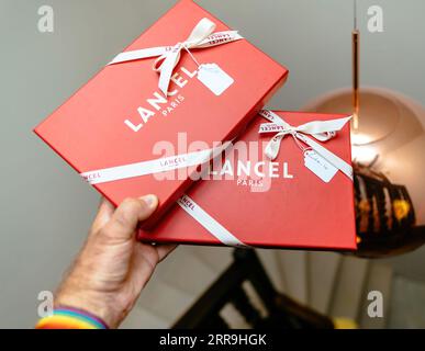 Paris, France - Aug 25, 2023: Male hand holding in luxury store two Lancel Paris expensive fashion items gifts in red packages Stock Photo