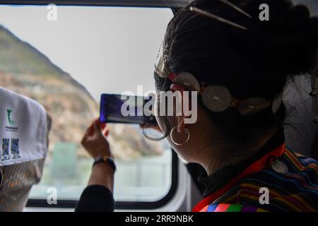 210625 -- LHASA, June 25, 2021 -- A passenger aboard the Fuxing bullet train takes photos of the scenery along the Lhasa-Nyingchi railway in southwest China s Tibet Autonomous Region, June 25, 2021. The first electrified railway in southwest China s Tibet Autonomous Region opened Friday morning, linking regional capital Lhasa with the city of Nyingchi, as Fuxing bullet trains enter official operation on the plateau region. With a length of 435 km and a designed speed of 160 km per hour, the new railway is a single-line electrified railway. Jigme Dorje CHINA-TIBET-LHASA-NYINGCHI RAILWAY-FUXING Stock Photo