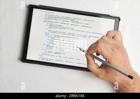 Programming and coding concept. A hand with a pencil writes a program listing on the screen Stock Photo