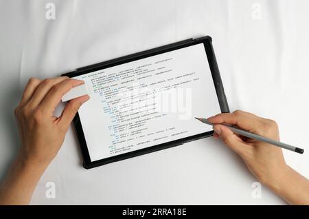 Programming and coding concept. Code generation: listing screen and two hands, one holding a pencil and the other holding an eraser Stock Photo