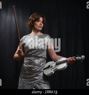 Half-length portrait of a woman playing the violin on a black background Stock Photo