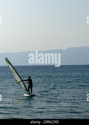 Recreational Water Sports. Windsurfing. Windsurfer Surfing The Wind On Waves In Ocean, Sea. Extreme Sport Action. Summer Fun Adventure. . High quality Stock Photo