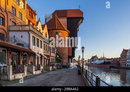 City of Gdańsk in Poland, sunrise in the Old Town with the Crane, historic apartment houses on Long Embankment (Długie Pobrzeże) street at Motława Riv Stock Photo