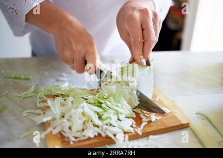 A girl cuts cabbage in the kitchen at home. Healthy eating at home. Stock Photo