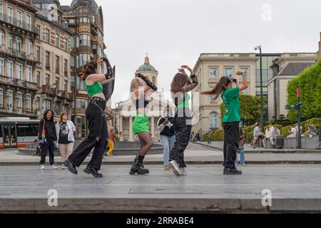 Brussels, Belgium - June 27 2023: Back view of street dancer girl group performing dance and tourists watch them Stock Photo