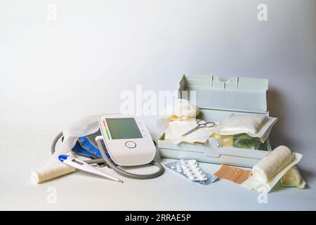 Important medical supplies for first aid and home medicine chest like blood pressure meter, fever thermometer, bandages, plasters and pills, light gra Stock Photo