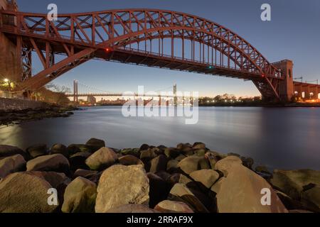 New York, New York, USA at Hell Gate Bridge at sunset over the East River at dusk. Stock Photo