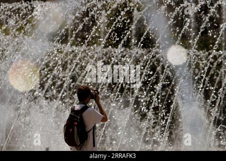 210728 -- BUCHAREST, July 28, 2021 -- A man takes pictures of a fountain during a hot day in downtown Bucharest, Romania, on July 28, 2021. Romanian authorities issued an orange code, announcing a heatwave with temperatures reaching 40 degrees in the south of the Balkan country in the next few days. Photo by /Xinhua ROMANIA-BUCHAREST-HEATWAVE CristianxCristel PUBLICATIONxNOTxINxCHN Stock Photo