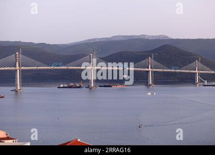 210729 -- KOMARNA, July 29, 2021 -- Photo taken on July 28, 2021 shows the final piece of steel box girder being lifted at Mali Ston Bay near Komarna of southern Croatia. The final piece of steel box girder for the Peljesac Bridge in southern Croatia was lifted and welded with the main structure on late Wednesday night. The 2.4-km cable-stayed bridge over the Mali Ston Bay of the Adriatic Sea connects Croatian mainland and the Peljesac Peninsula of its southernmost Dubrovnik-Neretva County, bypassing a short strip of Bosnian and Herzegovina s territory. /Pixsell via Xinhua CROATIA-KOMARNA-PELJ Stock Photo