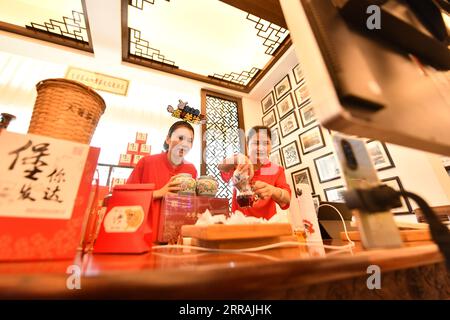 (230907) -- WUZHOU, Sept. 7, 2023 (Xinhua) -- Staff members sell tea products via livestreaming in a tea company in Wuzhou City, south China's Guangxi Zhuang Autonomous Region, Aug. 25, 2023. Liubao tea, a Chinese dark tea characterized by its strong and lingering fragrance and medical effects, boasts a history of more than 1,500 years. Famous for Liubao tea making, the city of Wuzhou has over 310,000 mu (about 20,667 hectares) of tea plantations and 269 tea cooperatives, with more than 50,000 people involved by the first half of 2023. (Xinhua/Huang Xiaobang) Stock Photo