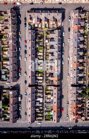 An aerial view directly above the rooftops of rows of back to back terraced houses with alleyways and gardens in a working class area of a Northern to Stock Photo
