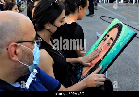 210804 -- BEIRUT, Aug. 4, 2021 -- A family member of Sahar Fares, a female firefighter martyr, touches Sahar s portrait at a commemoration marking the first anniversary of Beirut port blast in the headquarters of Beirut Fire Brigade, Lebanon, on Aug. 3, 2021. Various activities were held to mark the first anniversary of the Beirut port explosion. On Aug. 4, 2020, the Beirut port was hit by two big explosions, destroying a big part of Beirut, killing over 200 people, and injuring more than 6,000 others.  LEBANON-BEIRUT-BLAST-ANNIVERSARY LiuxZongya PUBLICATIONxNOTxINxCHN Stock Photo