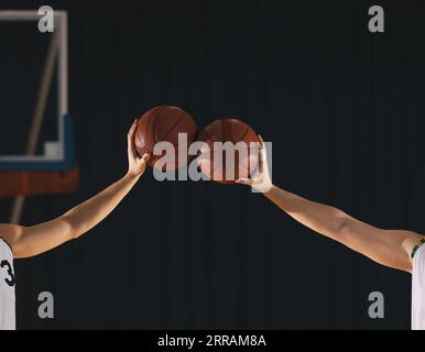 Two basketball players holding balls together on basketball court. Basketball team members on training drill Stock Photo