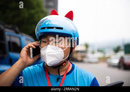 210809 -- ZHANGJIAJIE, Aug. 9, 2021 -- Delivery man Yan Yingzhao calls a resident to pick up a delivery order in Yongding District of Zhangjiajie, central China s Hunan Province, Aug. 9, 2021. Since last Tuesday, all the people in the central Chinese city of Zhangjiajie, including residents and tourists, are not allowed to leave the city as part of efforts to curb the latest resurgence of COVID-19. Local authorities have prioritized delivery services to ensure the supply of necessities. Couriers like 22-year-old Yan Yingzhao are working day and night to deliver food items and medical supplies Stock Photo