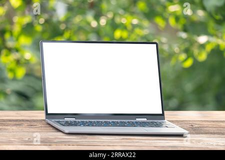 Laptop screen is blank are placed on wooden table and trees with nature that are beautiful on a light rainy day. Stock Photo