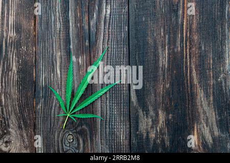 A hemp leaf on a wooden texture background close up Stock Photo