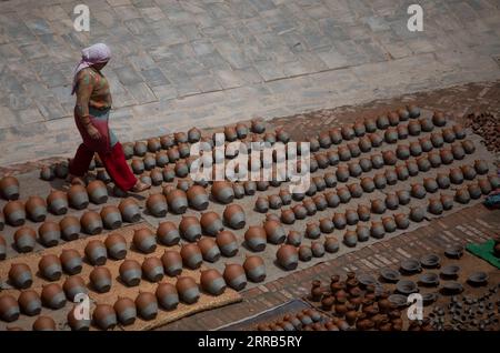 210902 -- BHAKTAPUR, Sept. 2, 2021 -- A woman looks after the clay pots kept for drying at a pottery square in Bhaktapur, Nepal, on Sept. 1, 2021. Bhaktapur is known for its centuries-old pottery craft, which has been passed down through generations. The pottery produced in Bhaktapur is regarded superior to those made elsewhere, owing to the usage of black clay which can be found only in one place and can only be dug once a year by Bhaktapur natives.  NEPAL-BHAKTAPUR-POTTERY CRAFT SulavxShrestha PUBLICATIONxNOTxINxCHN Stock Photo