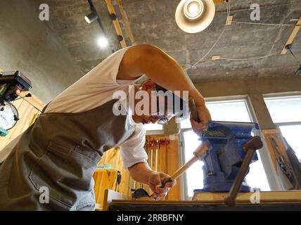 210919 -- SHIJIAZHUANG, Sept. 19, 2021 -- Li Zhanlong makes wooden mechanical installation at his studio in Luquan District of Shijiazhuang, north China s Hebei Province, Sept. 14, 2021. Li Zhanlong is a wooden mechanical installation designer in Shijiazhuang. After graduation, Li once worked as a salesman and ran an online shop. In 2018, Li Zhanlong left his job and went to Tianjin to learn carpentry skills. The wooden mechanical installation consists of a wooden figure and a mechanism device that can make the installation move. By shaking the handle or pressing the button, the installation c Stock Photo