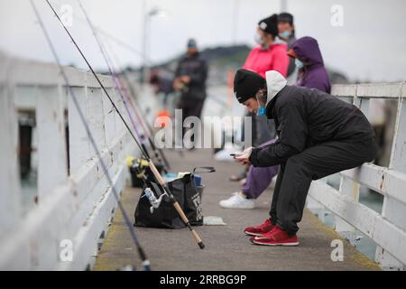 210921 -- AUCKLAND, Sept. 21, 2021 -- People go fishing at a wharf near Mission Bay of Auckland, New Zealand on Sept. 19, 2021. New Zealand s largest city Auckland will relax restrictions by moving to COVID-19 Alert Level 3 at 11:59 p.m. on Tuesday for at least two weeks, as the country reported 22 new Delta community cases on Monday. The city has remained at level 4, the top-level COVID-19 lockdown, for more than 30 days, longer than last year s lockdown, with schools and none-essential businesses closed. The rest of the country will stay at Alert Level 2, which means businesses and schools a Stock Photo