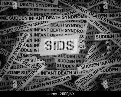 Strips of newspaper with the words SIDS (Sudden Infant Death Syndrome) typed on them. Black and white. Close up. Stock Photo