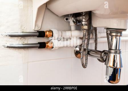 connection of polypropylene, flexible metal and plastic pipes under sink in bathroom Stock Photo