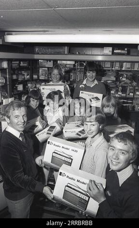 1981, inside a home appliances or electrical shop, a male shopkeeper  with excited young school children with their prizes of the latest portable transistor radios and cassette recorders, England. UK. The young wnners are holding  the Pye Radio Model 1420, while the cassette recorder is a Pye Model 9110. The Pye brand dates back to 1896 when William Pye started making scientific instruments in Cambridge under the name W. G Pye Ltd and then 1922 wireless components. In 1928 Pye sold the business, now called Pye Radio Ltd to C.O Stanley. Stock Photo