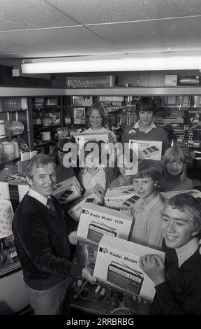 1981, inside a home appliances or electrical shop, a male shopkeeper  with excited young school children with their prizes of the latest portable transistor radios and cassette recorders, England. UK. The young wnners are holding  the Pye Radio Model 1420, while the cassette recorder is a Pye Model 9110. The Pye brand dates back to 1896 when William Pye started making scientific instruments in Cambridge under the name W. G Pye Ltd and then 1922 wireless components. In 1928 Pye sold the business, now called Pye Radio Ltd to C.O Stanley. Stock Photo