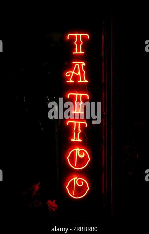 tattoos sign in red neon lights on black background Stock Photo