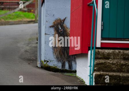 A playful mural of a sheep peeking around a house in the village of Funningur on the island of Eysturoy in the Faroe Islands. Stock Photo