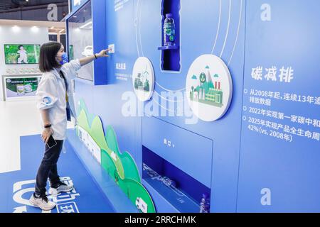 211107 -- SHANGHAI, Nov. 7, 2021 -- A staff member demonstrates how to use an intelligent plastic bottle recycling machine at the Food and Agricultural Products Exhibition Area of the 4th China International Import Expo CIIE in east China s Shanghai, Nov. 6, 2021. The intelligent plastic bottle recycling machine at Danone booth can recycle plastic bottles thrown away by visitors and turns them into soft fabrics. Fabrics made from 16 bottles can make a coat.  CIIECHINA-SHANGHAI-CIIE-EXHIBITION-BOTTLE RECYCLING CN ZhangxYuwei PUBLICATIONxNOTxINxCHN Stock Photo