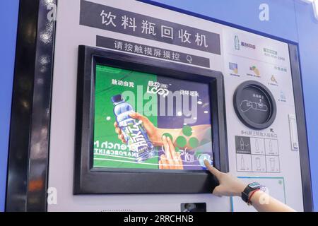 211107 -- SHANGHAI, Nov. 7, 2021 -- A staff member demonstrates how to use an intelligent plastic bottle recycling machine at the Food and Agricultural Products Exhibition Area of the 4th China International Import Expo CIIE in east China s Shanghai, Nov. 6, 2021. The intelligent plastic bottle recycling machine at Danone booth can recycle plastic bottles thrown away by visitors and turns them into soft fabrics. Fabrics made from 16 bottles can make a coat.  CIIECHINA-SHANGHAI-CIIE-EXHIBITION-BOTTLE RECYCLING CN ZhangxYuwei PUBLICATIONxNOTxINxCHN Stock Photo