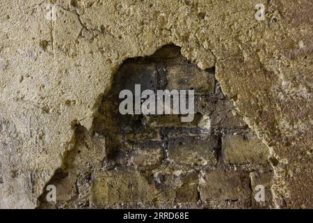 crumbling plaster on an old brick wall Stock Photo