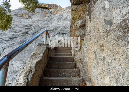 Empty narrow stairway with metal handrails leading up a rocky mountain peak Stock Photo