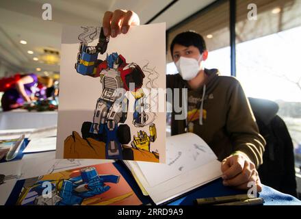 211212 -- MISSISSAUGA, Dec. 12, 2021 -- An illustrator shows one of his works during the TFcon Toronto 2021 in Mississauga, Canada, Dec. 11, 2021. As one of the largest fan-run Transformers conventions in the world, the TFcon Toronto event is held in Mississauga from Friday to Sunday. Photo by /Xinhua CANADA-MISSISSAUGA-TRANSFORMERS CONVENTION ZouxZheng PUBLICATIONxNOTxINxCHN Stock Photo