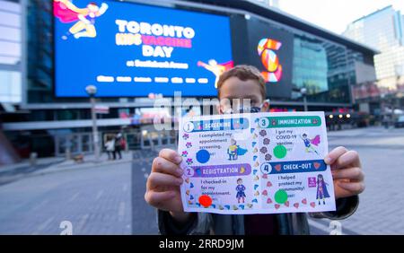 211212 -- TORONTO, Dec. 12, 2021 -- A boy wearing a face mask poses for photos with a COVID-19 vaccination passport after being vaccinated outside a vaccination site in Toronto, Canada, on Dec. 12, 2021. The City of Toronto on Sunday hosted a superhero-themed mass vaccination event as Toronto Kids Vaccine Day to vaccinate up to 2,000 children aged five to 11 against COVID-19. Photo by /Xinhua CANADA-TORONTO-KIDS VACCINE DAY ZouxZheng PUBLICATIONxNOTxINxCHN Stock Photo