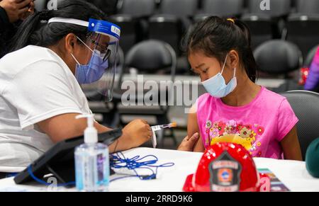 211212 -- TORONTO, Dec. 12, 2021 -- A vaccinator wearing a face mask and a face shield prepares to administer the COVID-19 vaccine to a child at a vaccination site in Toronto, Canada, on Dec. 12, 2021. The City of Toronto on Sunday hosted a superhero-themed mass vaccination event as Toronto Kids Vaccine Day to vaccinate up to 2,000 children aged five to 11 against COVID-19. Photo by /Xinhua CANADA-TORONTO-KIDS VACCINE DAY ZouxZheng PUBLICATIONxNOTxINxCHN Stock Photo