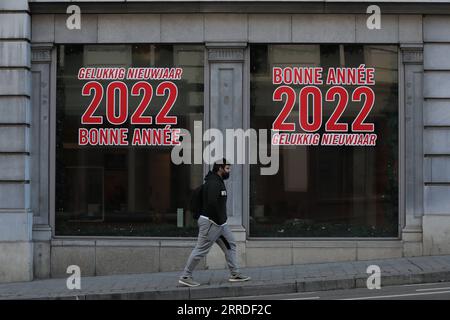 211221 -- BRUSSELS, Dec. 21, 2021 -- A man walks past windows with words Happy New Year 2022 in Brussels, Belgium, on Dec. 21, 2021. Belgium is in the midst of a new wave of COVID-19 pandemic due to the Omicron variant, which represented 20 percent of all positive test results across the country reported Monday morning, according to microbiologist Emmanuel Andre.  BELGIUM-BRUSSELS-COVID-19-OMICRON VARIANT ZhengxHuansong PUBLICATIONxNOTxINxCHN Stock Photo