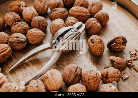 walnuts and a nutcracker in a round bowl on a wooden table. Healthy food and snacks.Healthy fats. Stock Photo