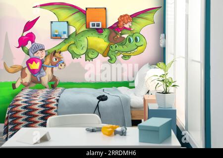 Kid's room interior with comfortable bed and other furniture. Fairytale themed wallpapers with dragon, knight and princess Stock Photo