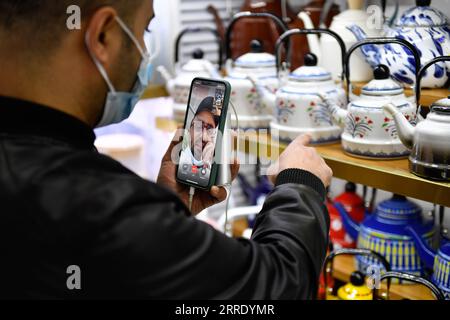 220114 -- SHANGHAI, Jan. 14, 2022 -- A Yemeni trader selects tea pots while communicating with his Saudi Arabian client via video link at the Yiwu International Trade Market in Yiwu city of east China s Zhejiang Province, Jan. 14, 2021. China s foreign trade moved up another notch in 2021, exceeding 6 trillion U.S. dollars for the first time, despite the COVID-19 pandemic continuing to weigh on global trade, official data showed Friday. The total trade in goods amounted to 6.05 trillion U.S. dollars, up 1.4 trillion U.S. dollars from a year ago, according to the General Administration of Custo Stock Photo