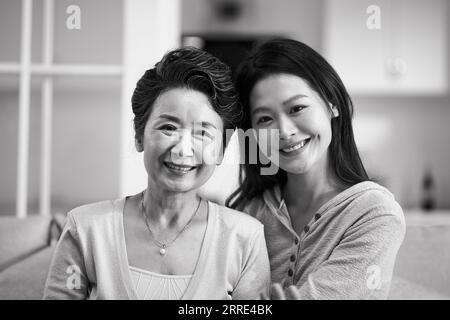 portrait of asian senior mother and adult daughter looking at camra smiling, black and white Stock Photo